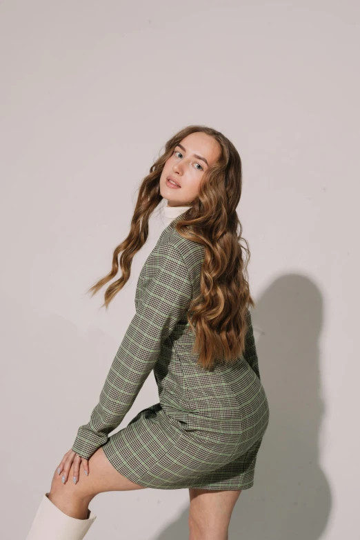 a girl sitting on the ground wearing a green dress and boots