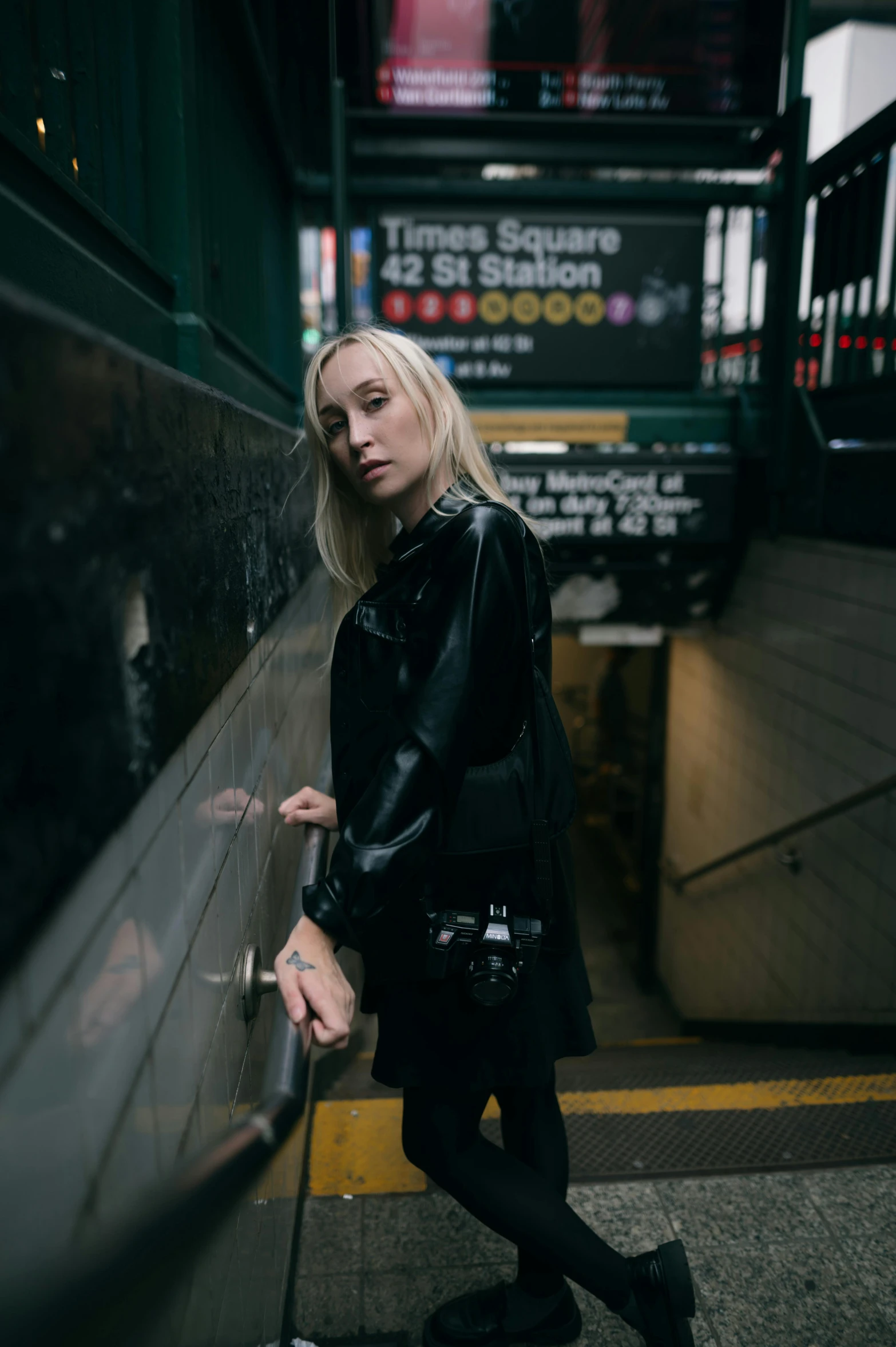 a girl in black dress standing in the subway