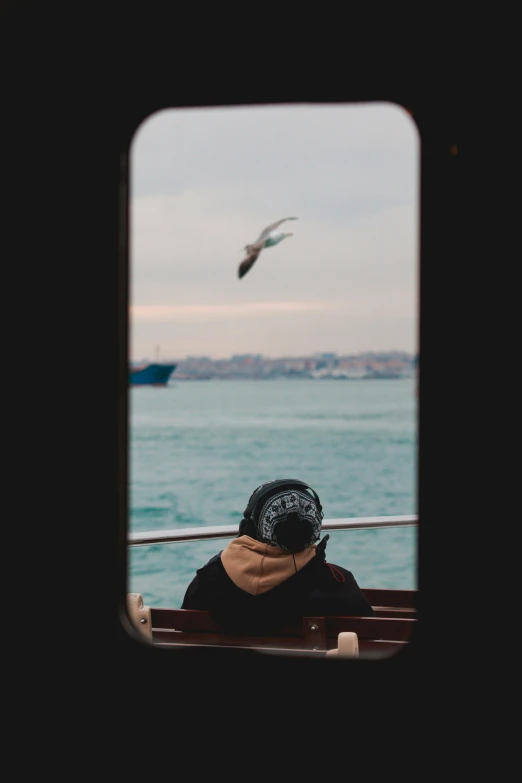 a woman is sitting on a boat with seagulls in the background