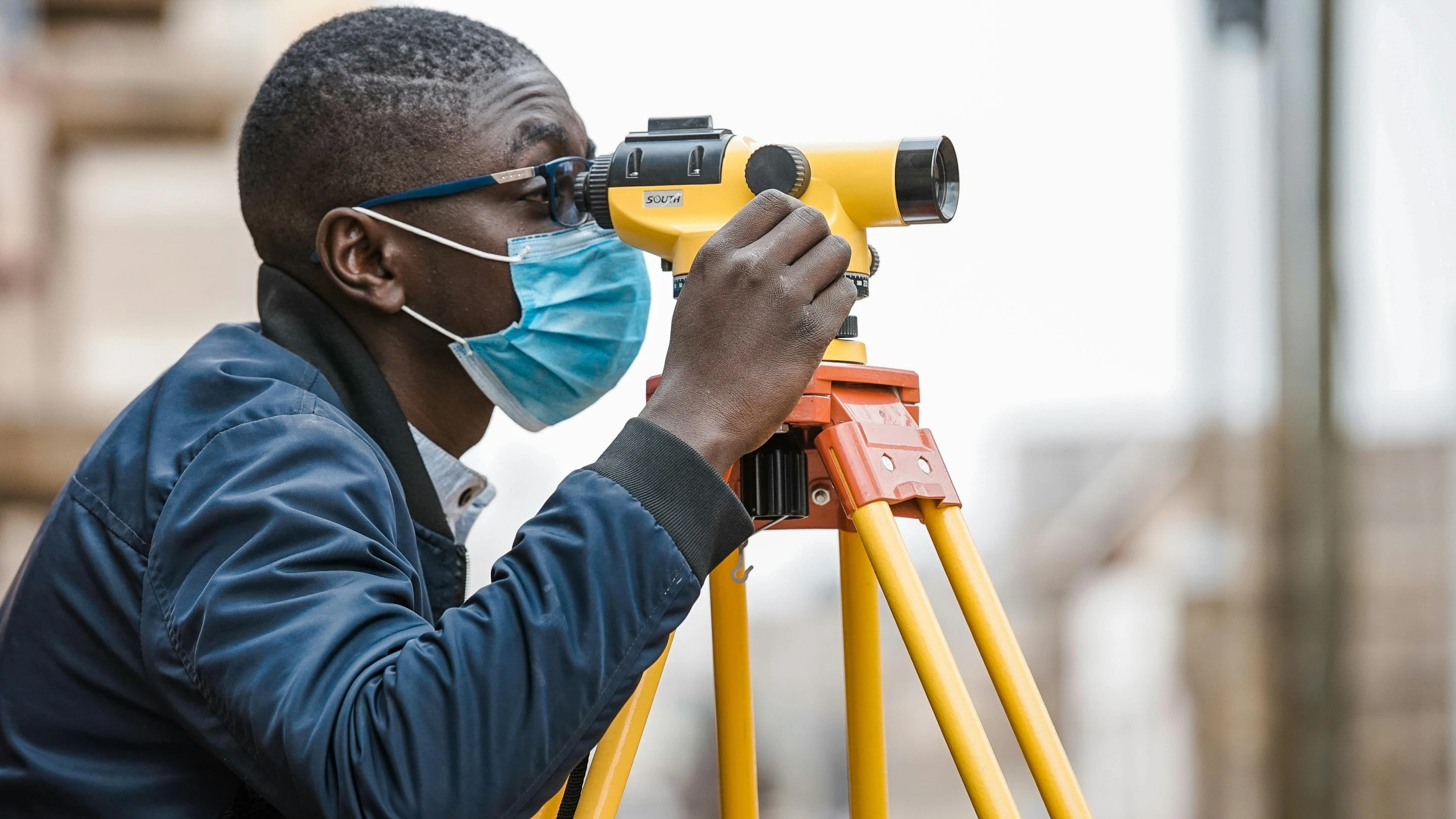 man with medical mask on looking through bins of a surveying machine