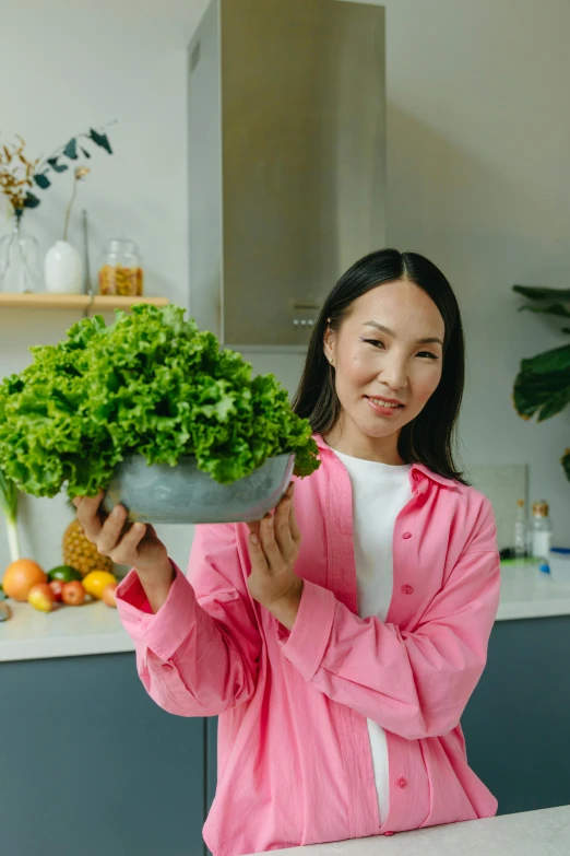 a woman holding up a bowl of vegetables in her hands