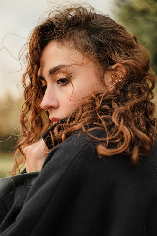 a young woman is wearing a black sweatshirt and she has long curly red hair
