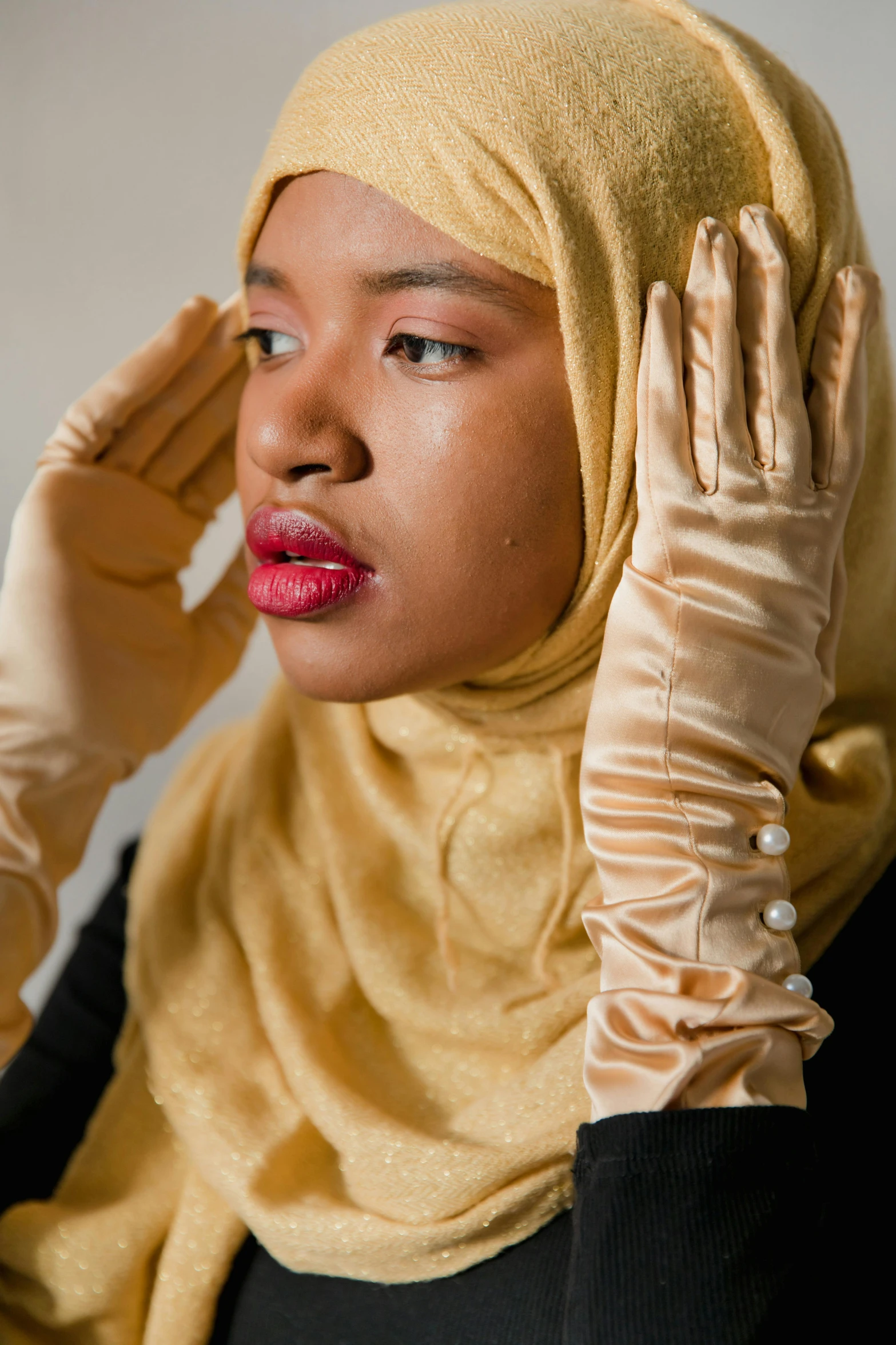 a woman with her hair in a hijab, wearing a pair of gloves