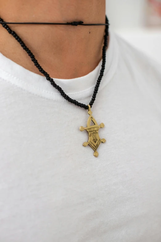 an intricate necklace features a gold pendant with the symbols of the two human creatures