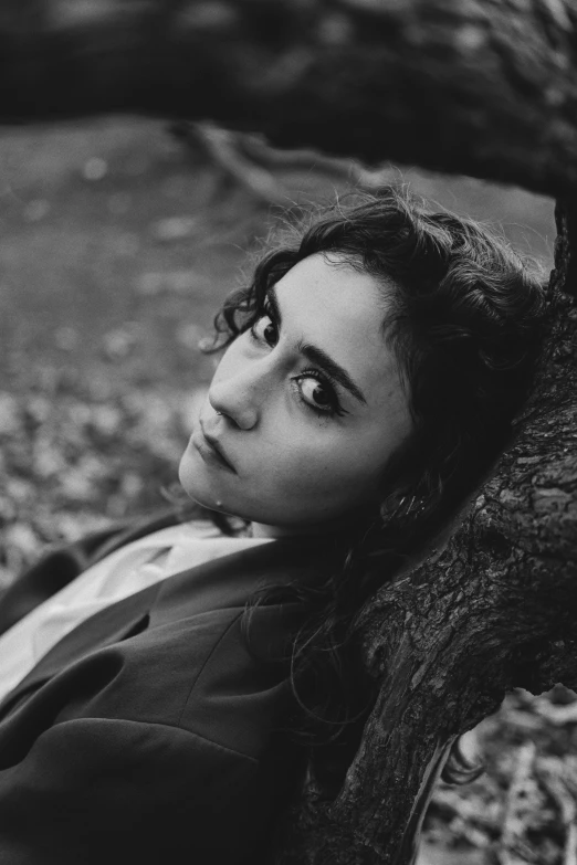 black and white po of young woman leaning up against tree