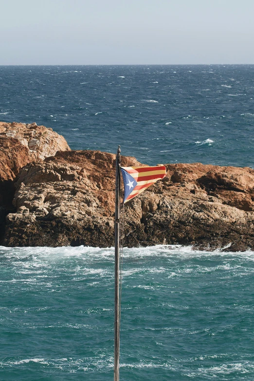 a flag is waving on a rocky beach