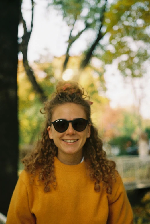 a woman wearing a yellow sweater smiling at the camera