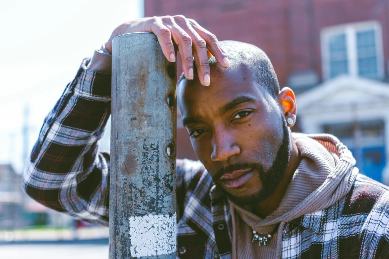 a man leaning against a post in front of a brick building