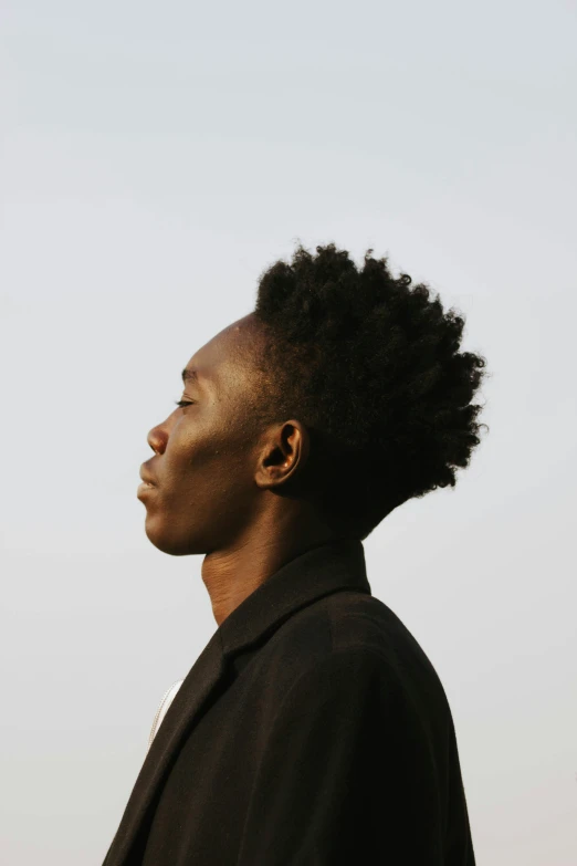 man with large, curly hair standing in the sun