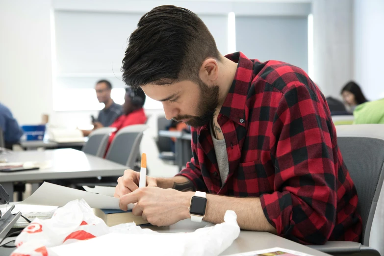 young male student taking notes and studying in classroom