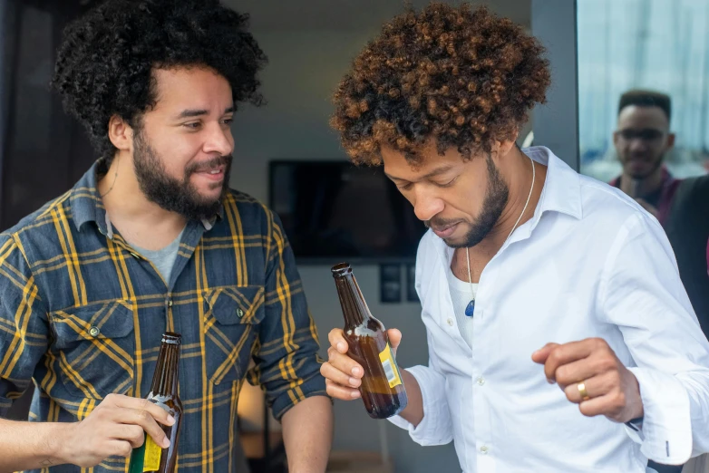 two men are in a public gathering holding beer