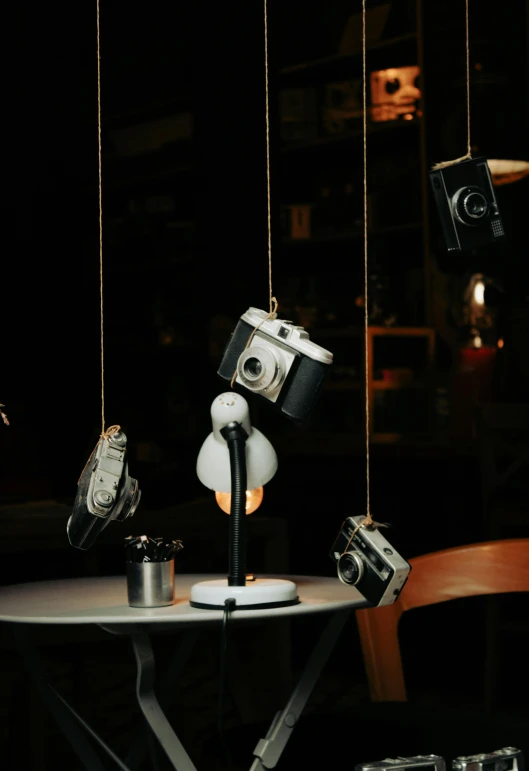 several old and vintage cameras hang from a table