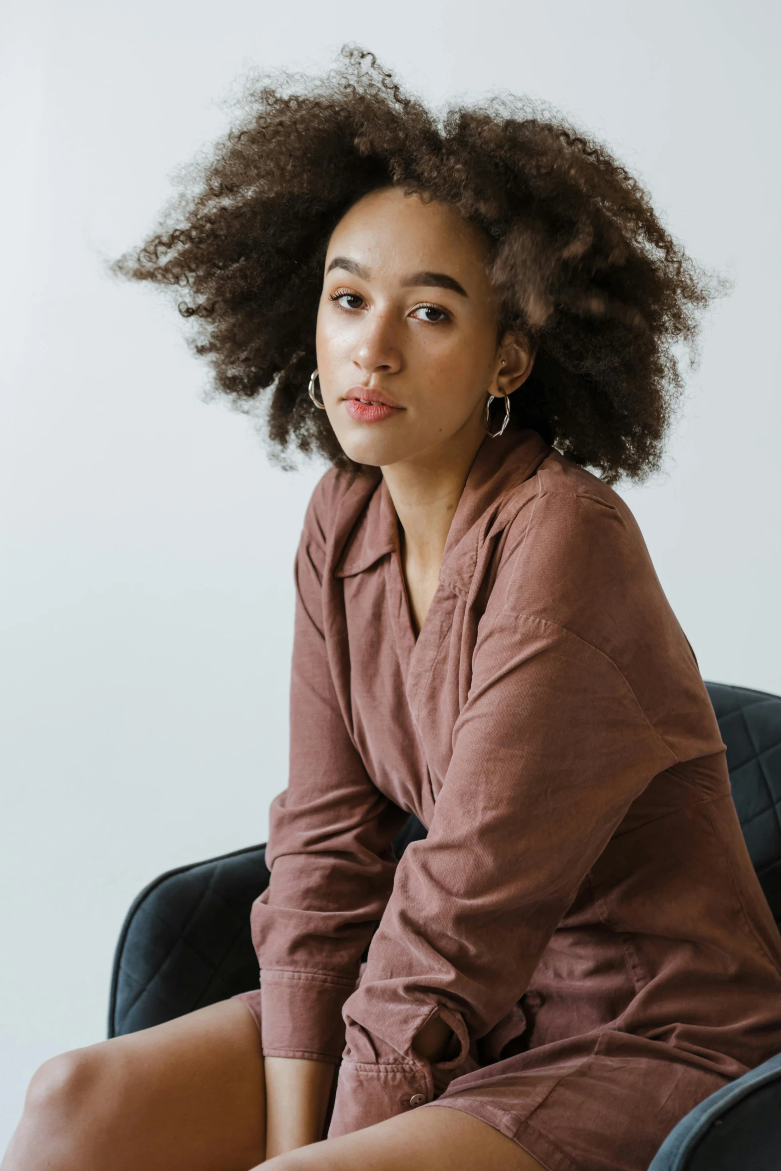 a young woman with long, dark hair sitting on a chair and looking away