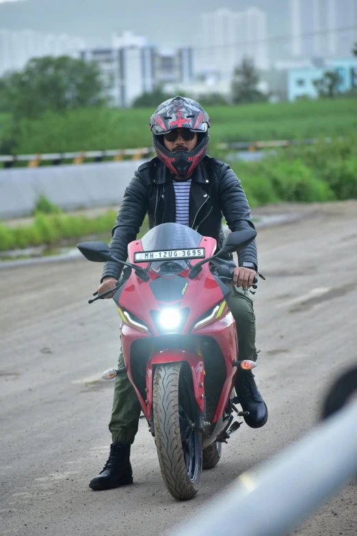 person on red motorcycle sitting on roadway near fence