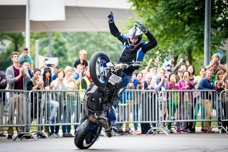 a motorcycle rider performing a stunt on the street in front of a crowd