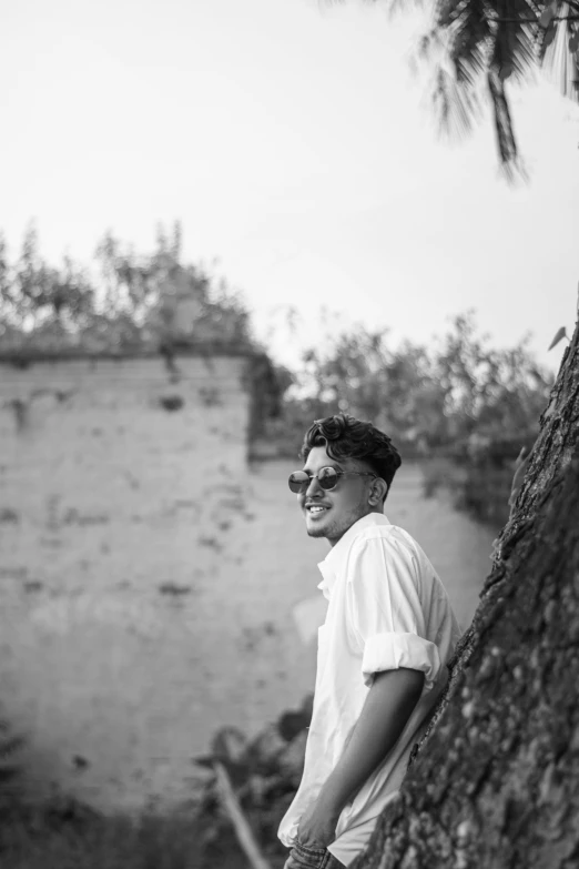 a man leaning up against a tree next to a river