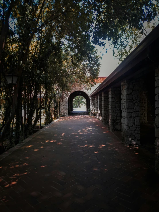 an archway between buildings surrounded by tree lined walkway