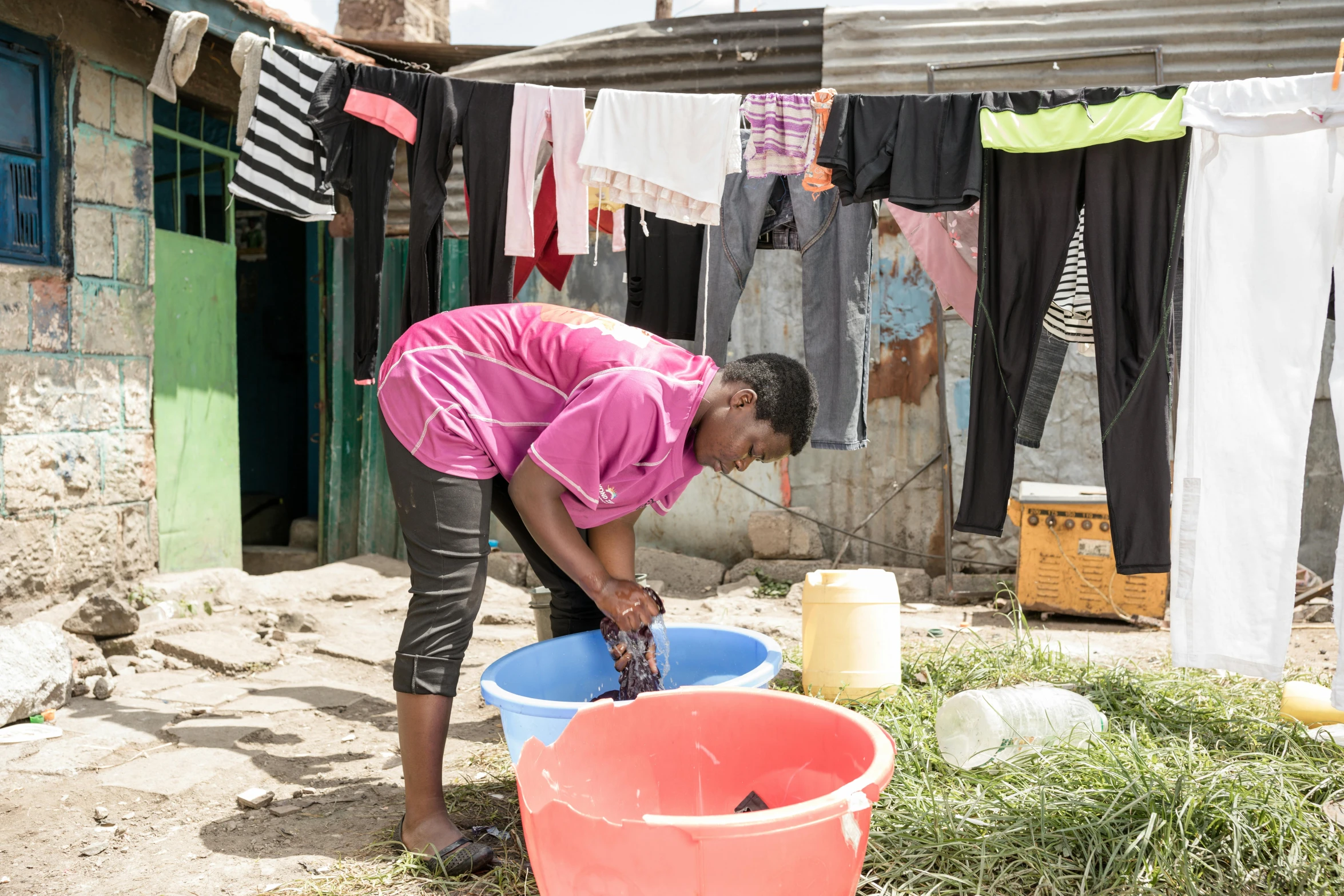 a woman is washing her clothes in a bucket outside