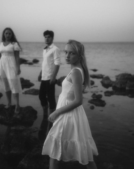 three young people stand by the ocean looking forward