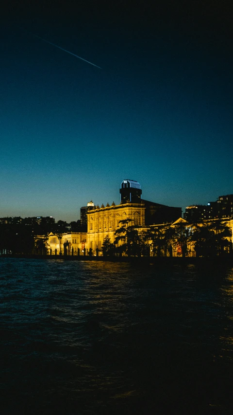 the building near the water is lit up in bright yellow