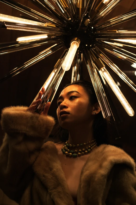 a woman is standing in front of a light fixture