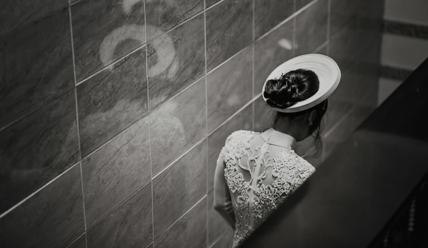 black and white po of a lady in hat against a wall