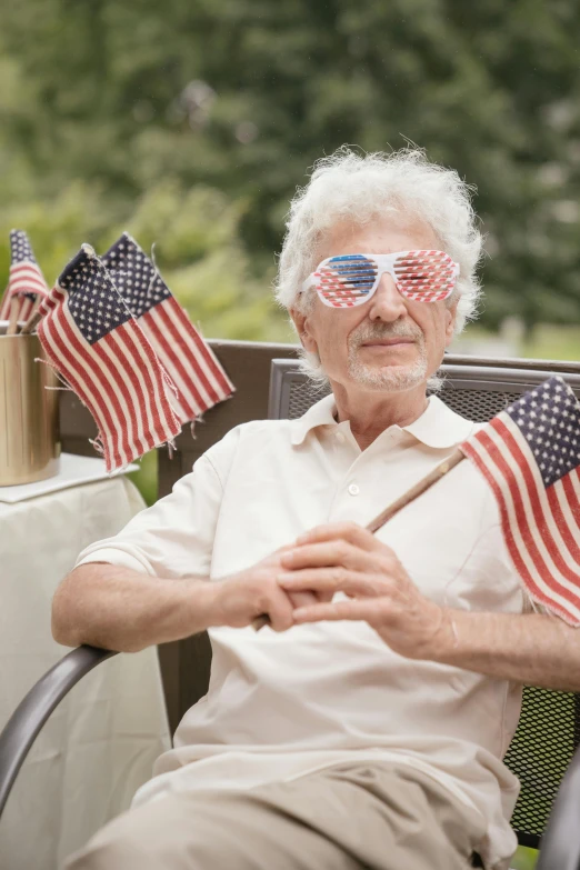 an elderly man wearing american flags sunglasses while sitting