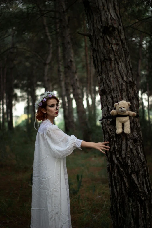 a woman dressed in white poses with her teddy bear