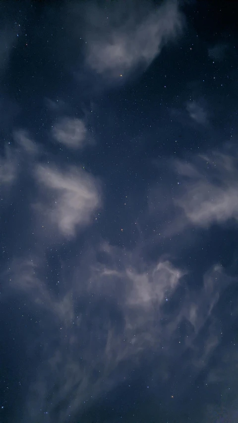 a night sky with stars and clouds above a building