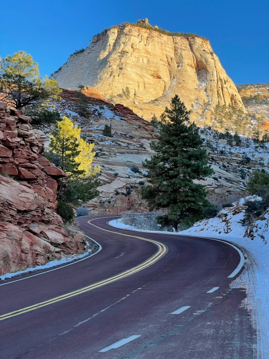 a curveed road with trees and a mountain in the background