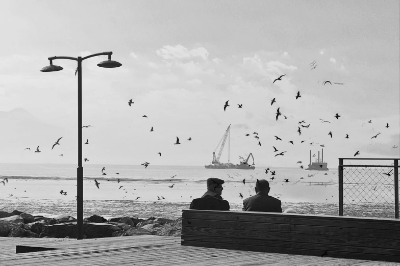 a couple of men sitting on top of a bench near the ocean