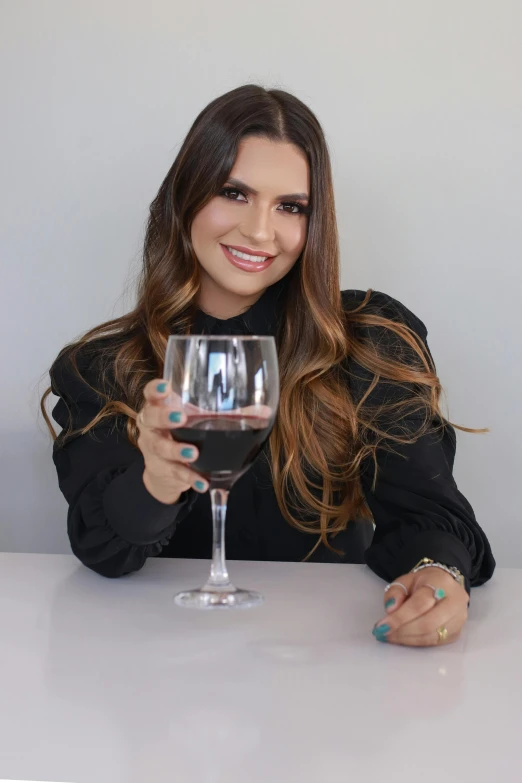 a woman holds a glass of wine while sitting at a table