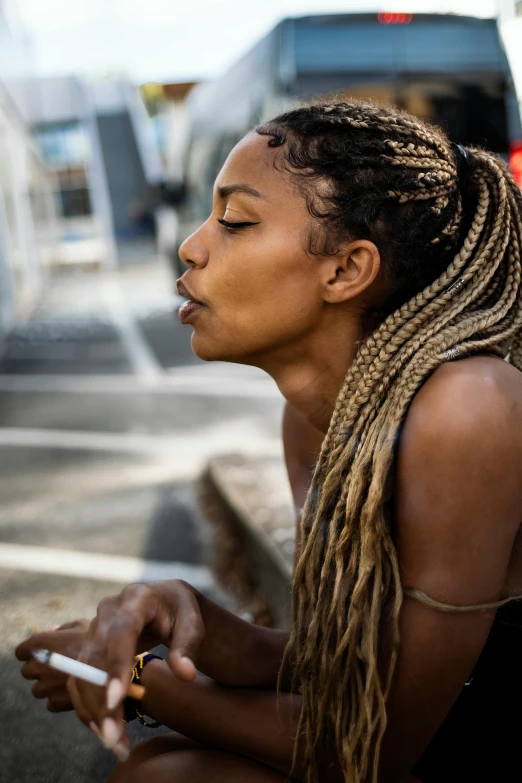 a woman sitting outside smoking a cigarette and looking off into the distance