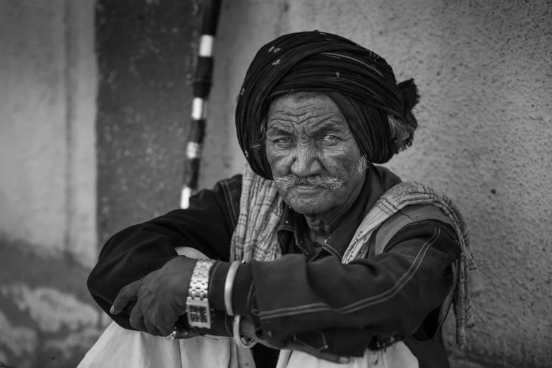 an old man sitting down with his hands clasped