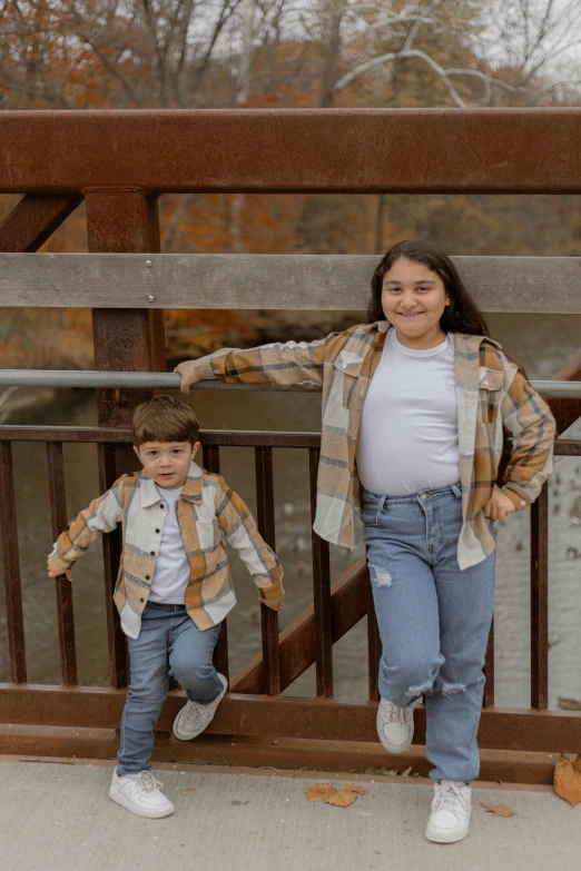 two small children stand by a bridge in front of the camera