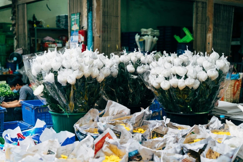 an outdoor vegetable market that is filled with lots of white flowers