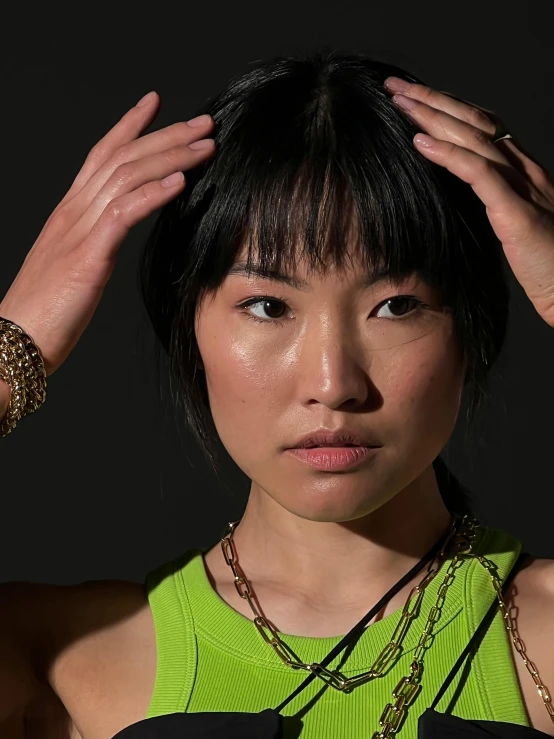 a woman with short dark hair and green shirt holding her head