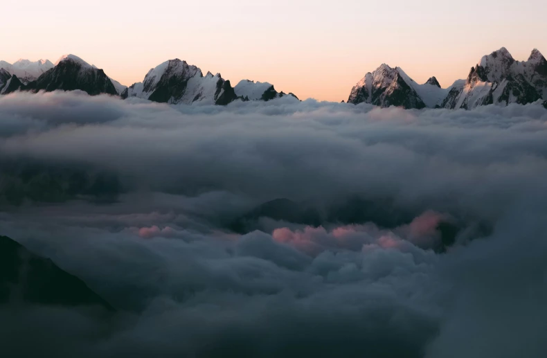 an aerial view of some snowy mountains and clouds