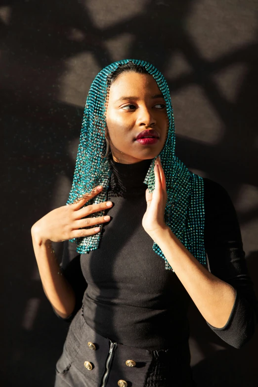 a woman in black dress and teal beaded head wrap