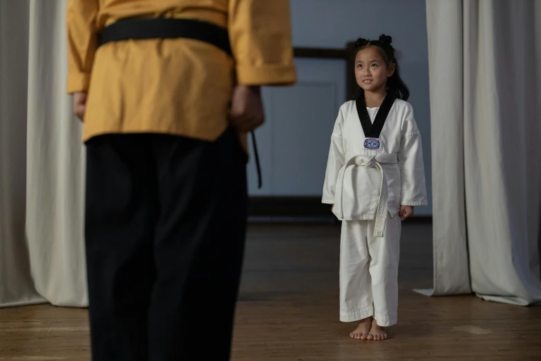 a  in a karate uniform with her karate instructor in the background