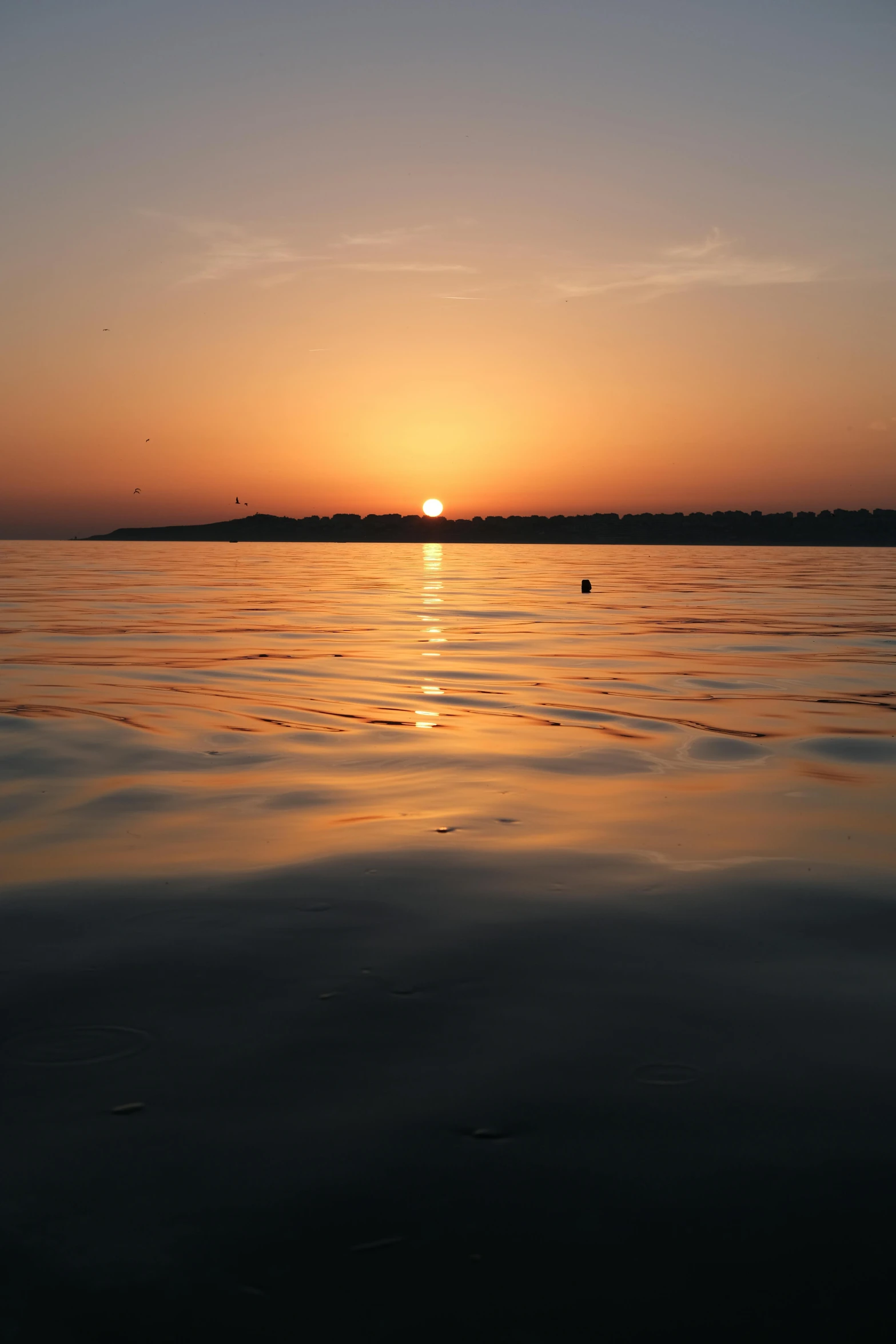 the sun is setting in front of a lake