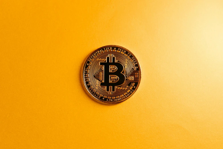 a bit coin sitting in front of a yellow wall