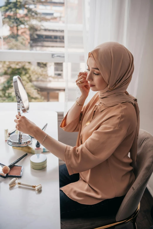 a woman sitting at a desk looking in the mirror