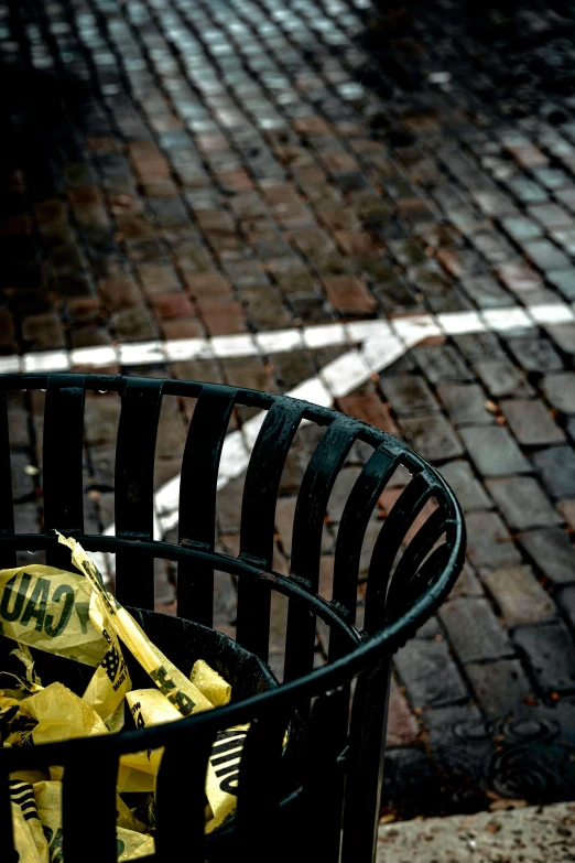 a garbage basket sitting on a street curb