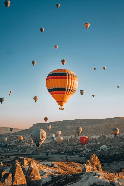 a bunch of balloons flying in the air over rocks