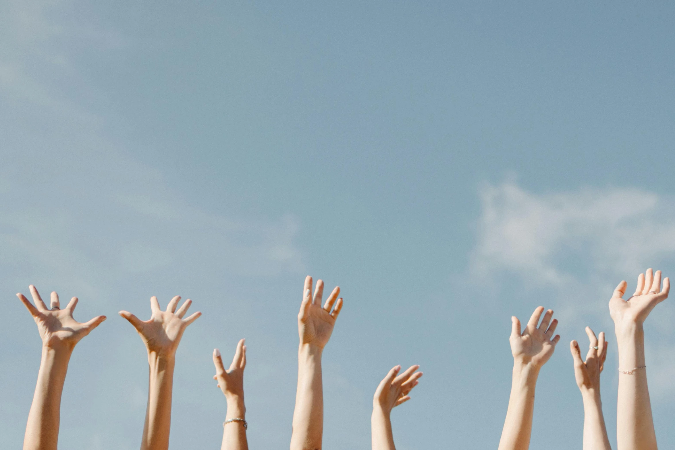 people's hands reaching up into the air