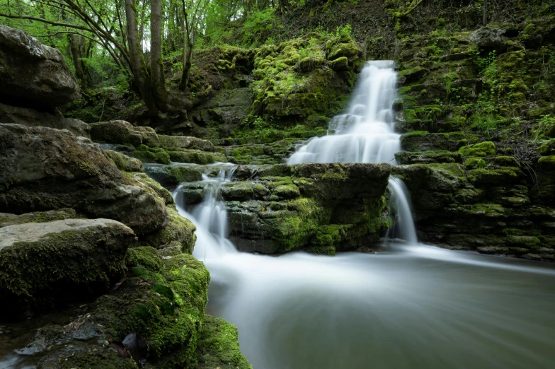 this is a waterfall that is surrounded by green plants and rocks