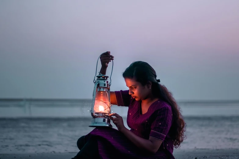 a woman holds an old - fashioned light at the beach