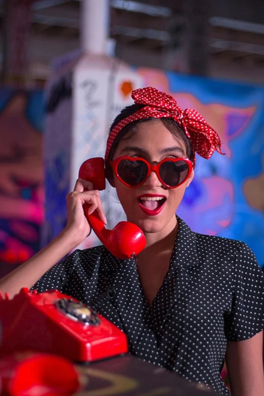 a young lady wearing sunglasses talking on the telephone