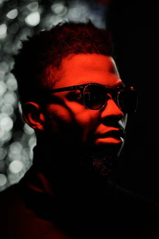 a man in sunglasses is shown with dark lights behind him